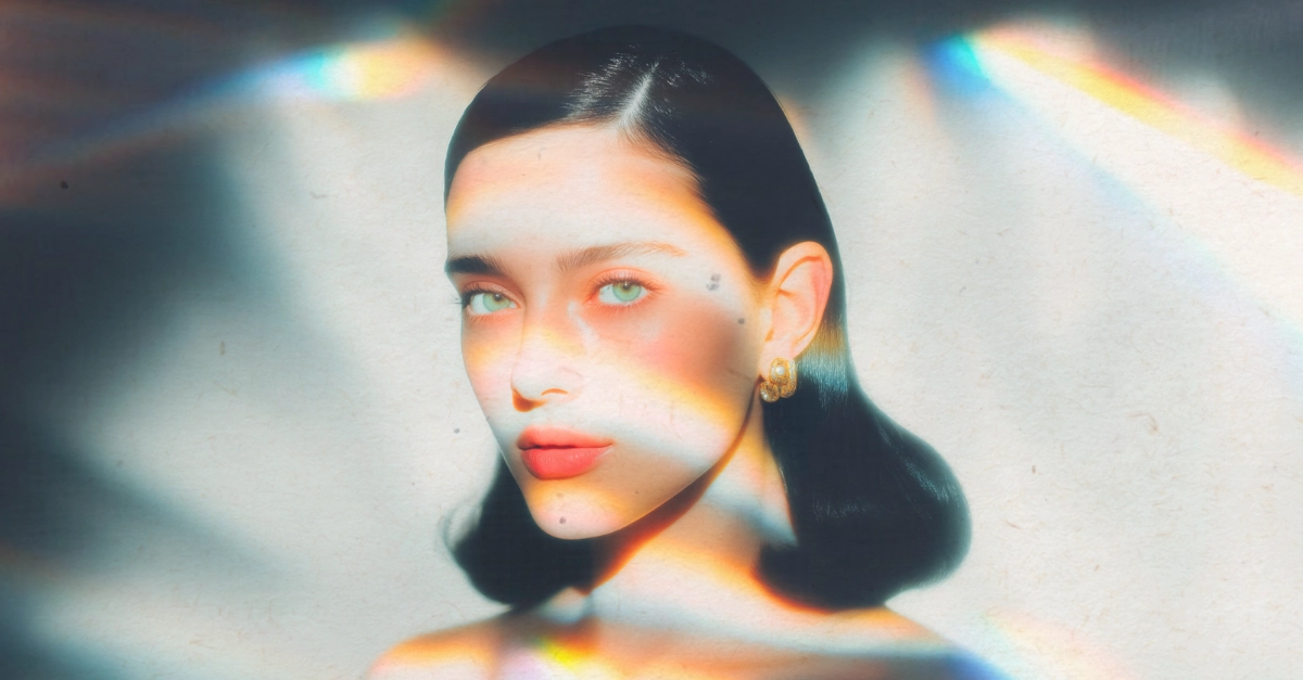 Un portrait artistique d'une jeune femme au regard mélancolique traversé par un prisme de lumière colorée, symbolisant le mystère et le détachement émotionnel quand un partenaire cherche à comprendre pourquoi les femmes quittent les hommes.