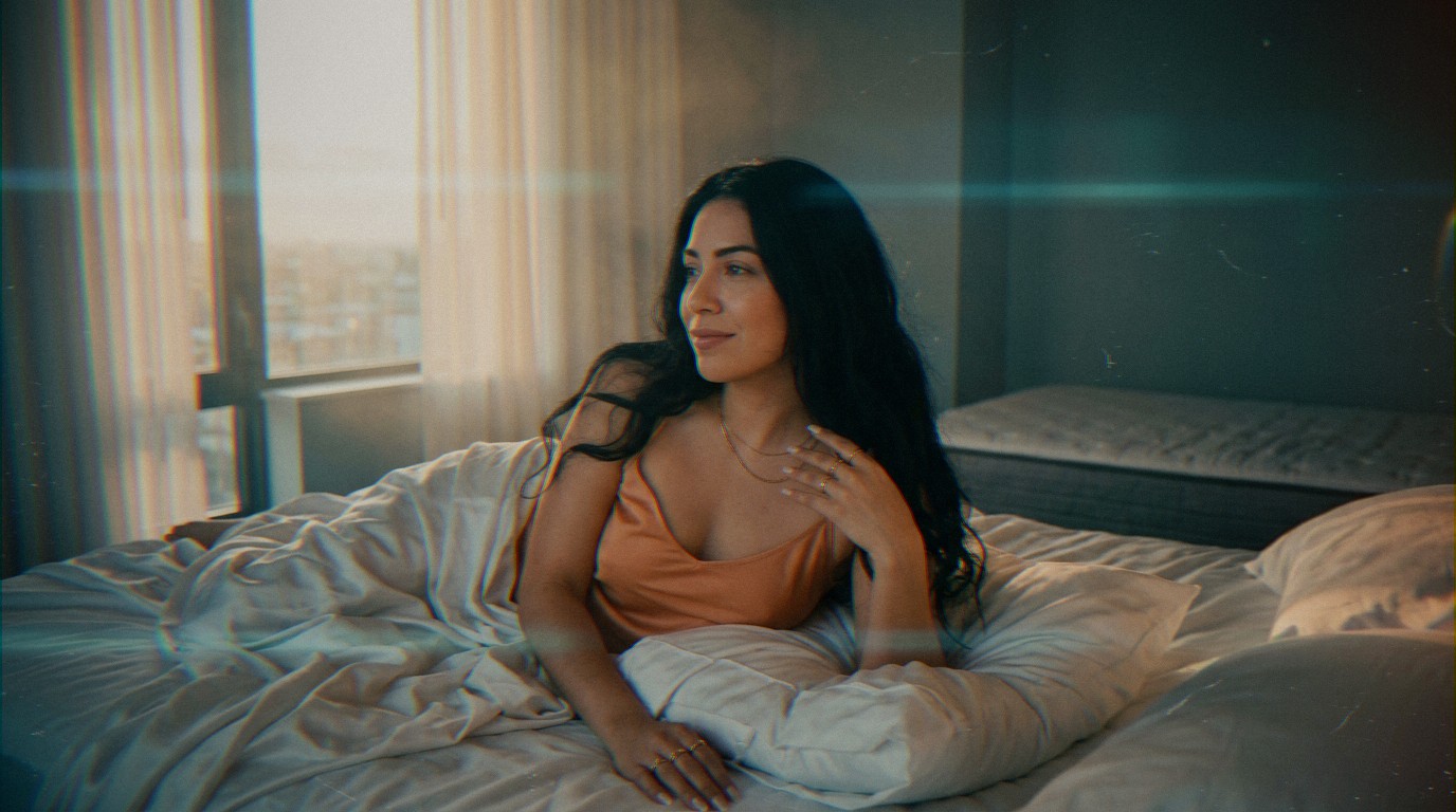 Une belle femme latine songeuse sur son lit, cheveux noirs et ondulés. Elle médite après avoir dit 'j'ai quitté ma copine'.